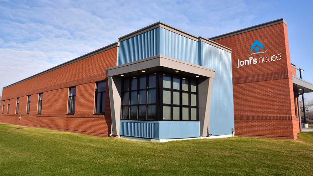 A brick and turquoise building with the words Joni's House