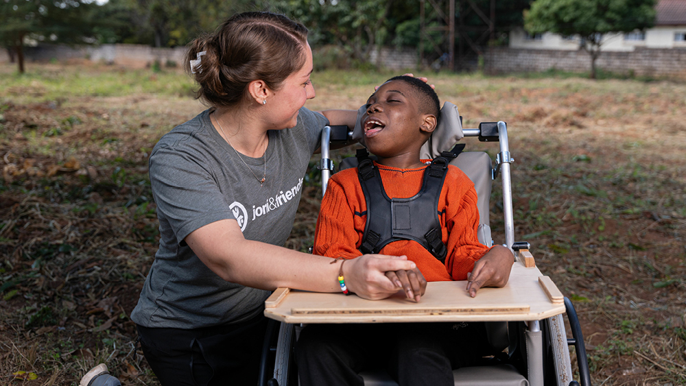 A volunteer and boy in a wheelchair pose for a photo