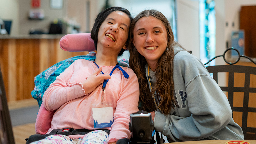 A camper and volunteer pose for a photo at Family Retreat