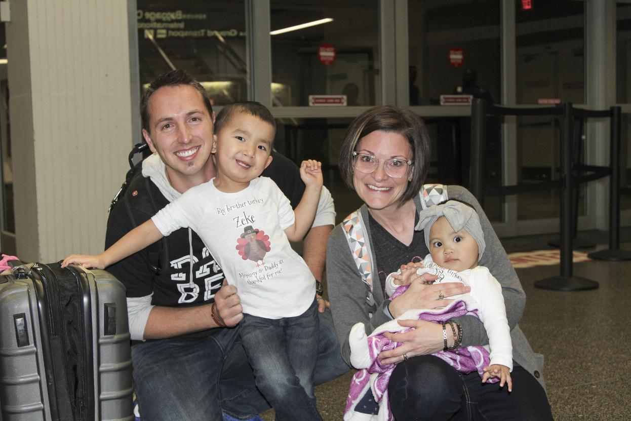 First family photo at the airport of Justin and Molly with their son Zeke and daughter Isla, with their luggage by their side.