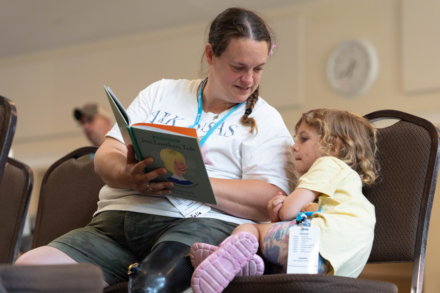Julia is sitting and reading a children’s book to her daughter.