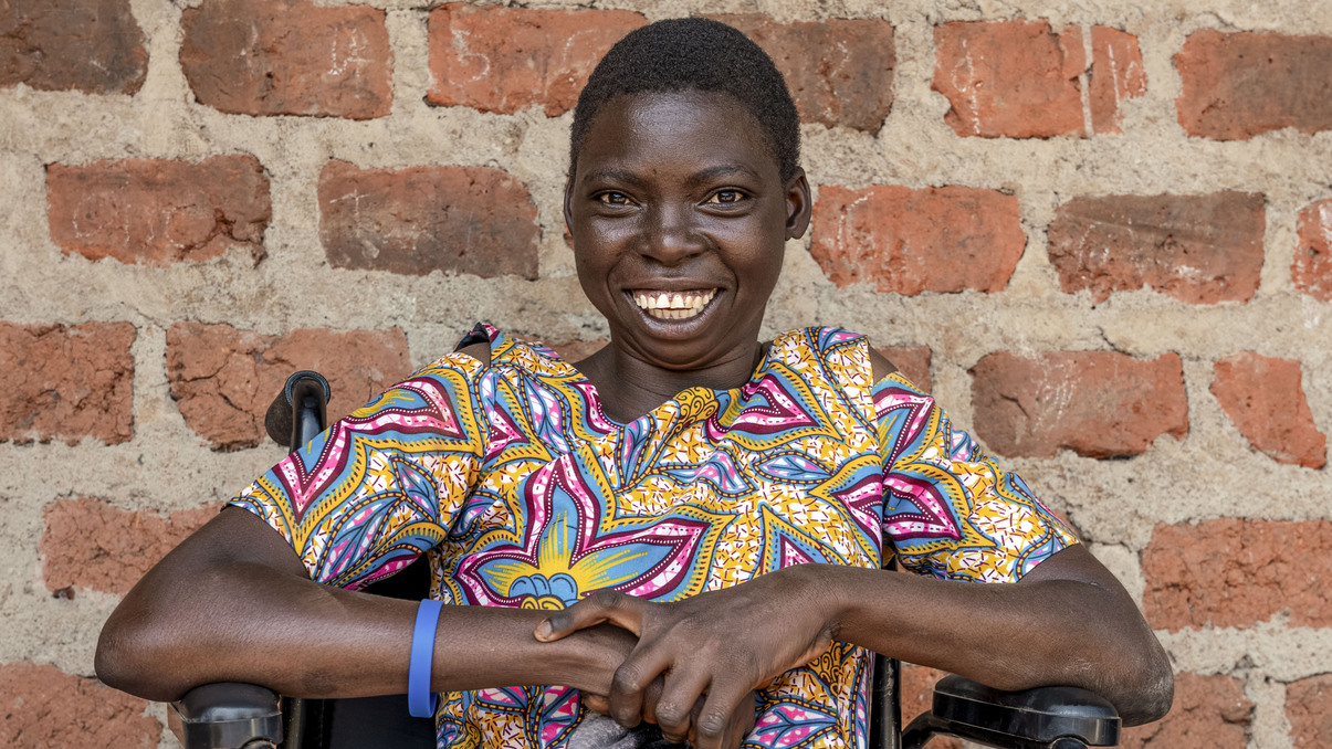 A woman smiling for the camera in front of a brick wall.