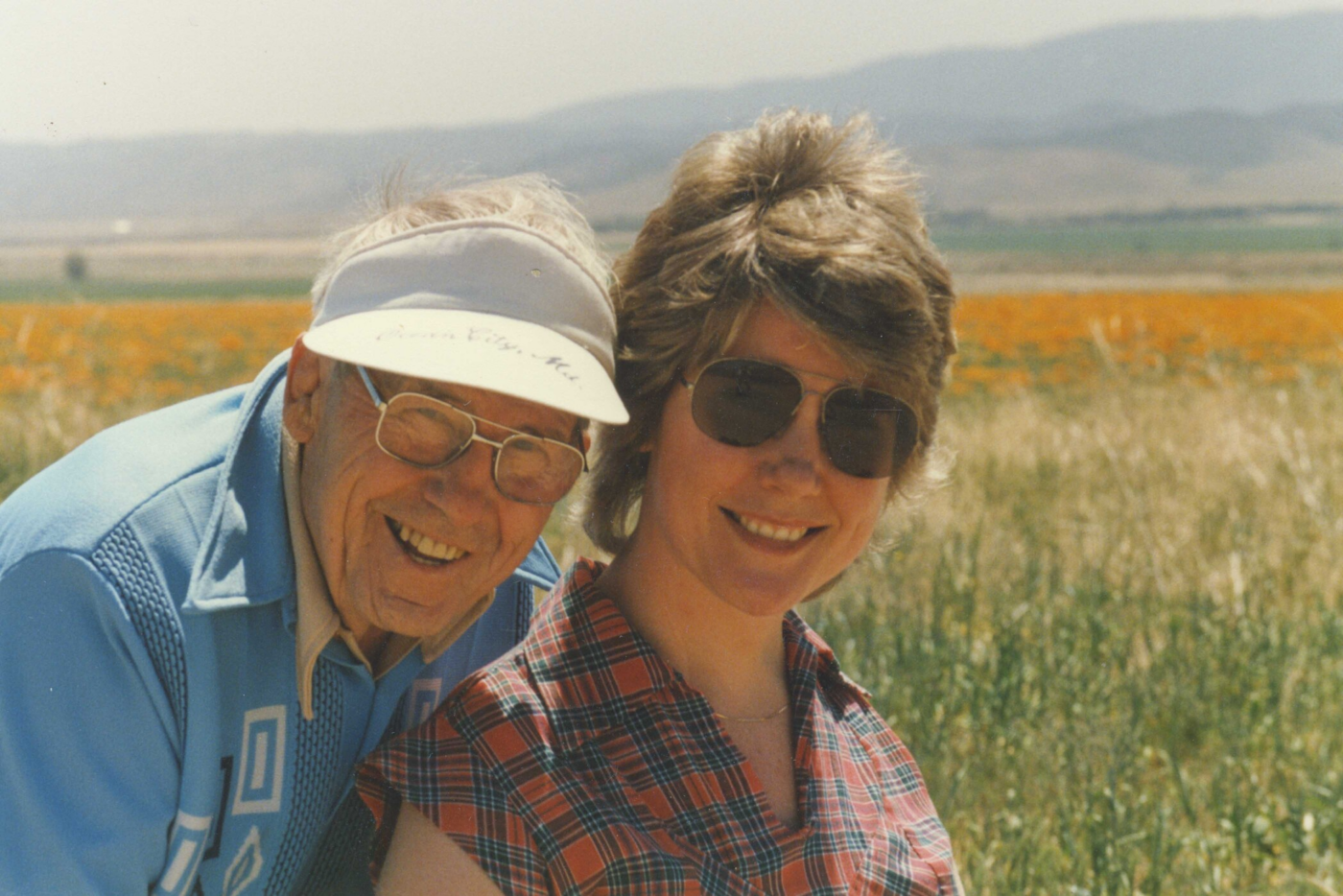 John King Eareckson and Joni Eareckson Tada smile together in a sunlit grassy field.
