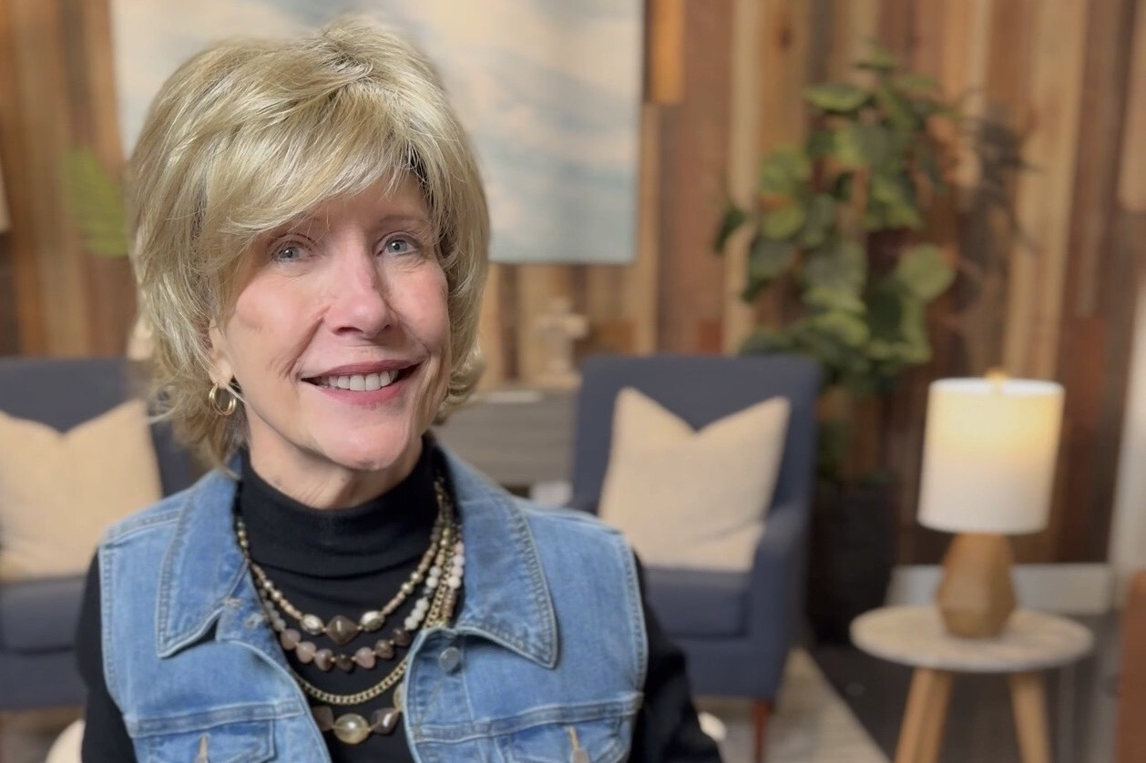 Joni Eareckson Tada beside her book Keeping Faith When Life Hurts in a cozy living room setting.