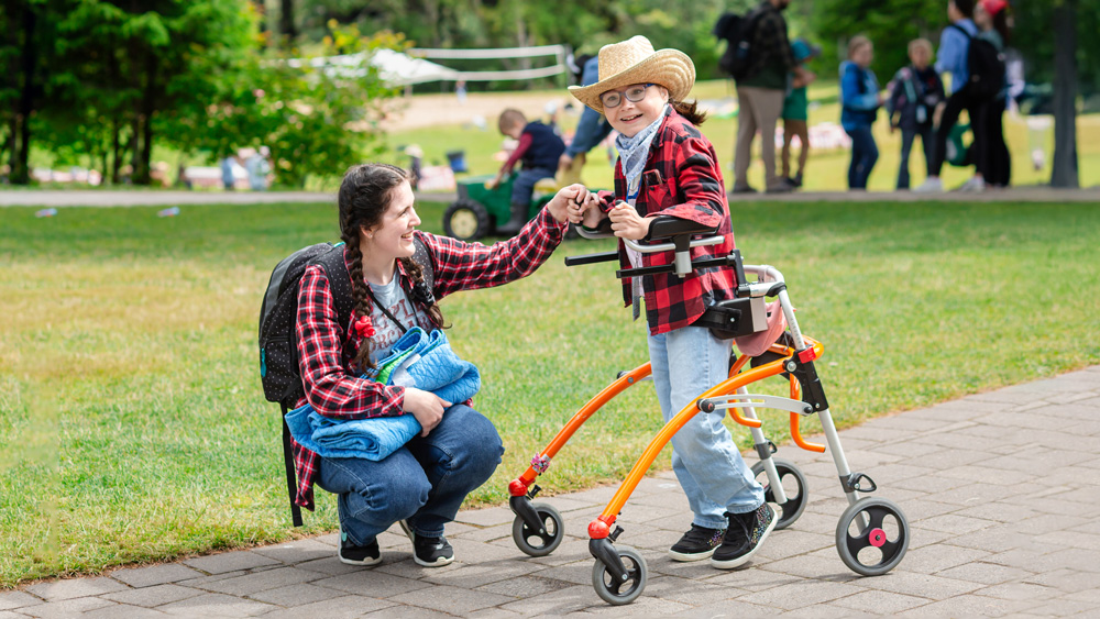 A volunteer and boy in his walker pose for a photo