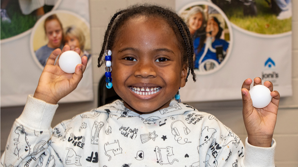 A girl holding two ping pong balls