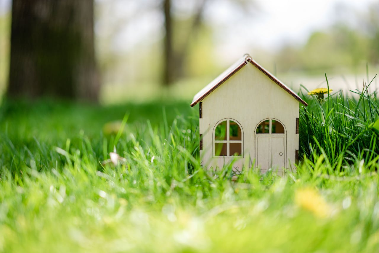 A miniature house made of cardboard on the grass.