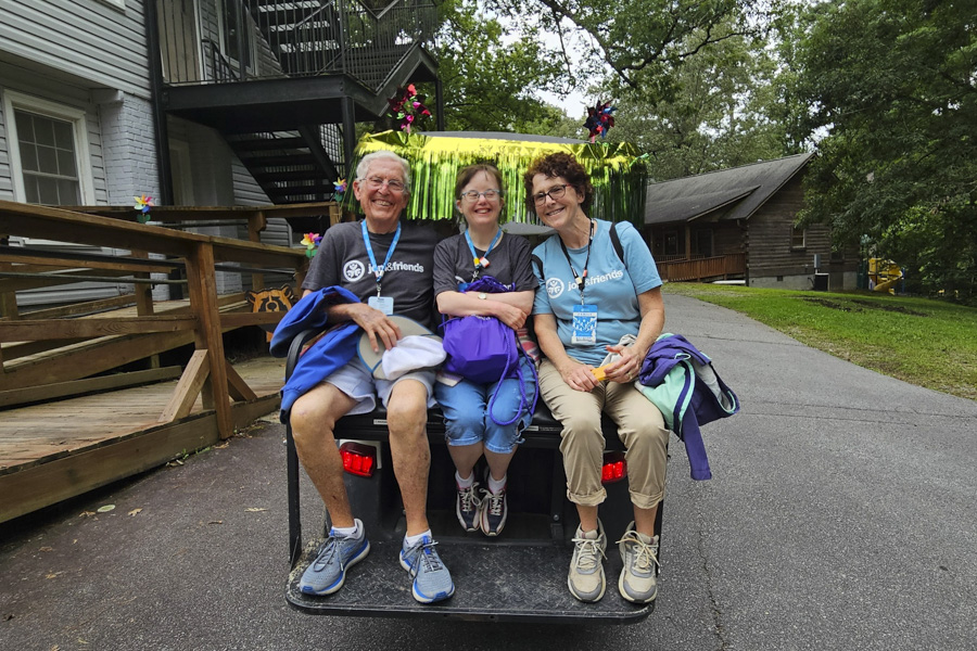 Ron, Jenny, and another woman sit in the back of a decorated gold cart, smiling and posing for a group photo.