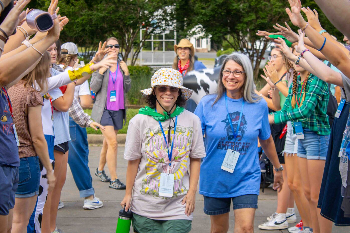 A group of campers forms a cheering tunnel with raised arms as Bailey and her mom, Lorna, walk through.
