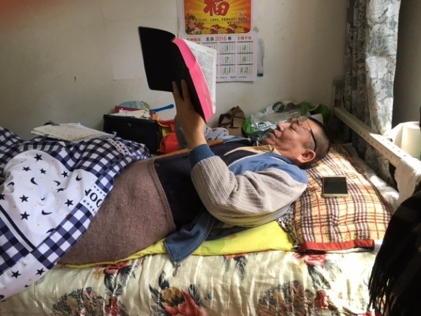 Mr. Wang reading his Bible in bed