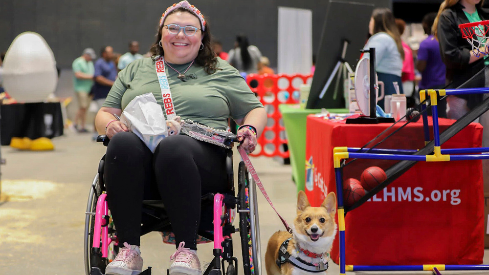 A woman smiles in her wheelchair with her dob beside her