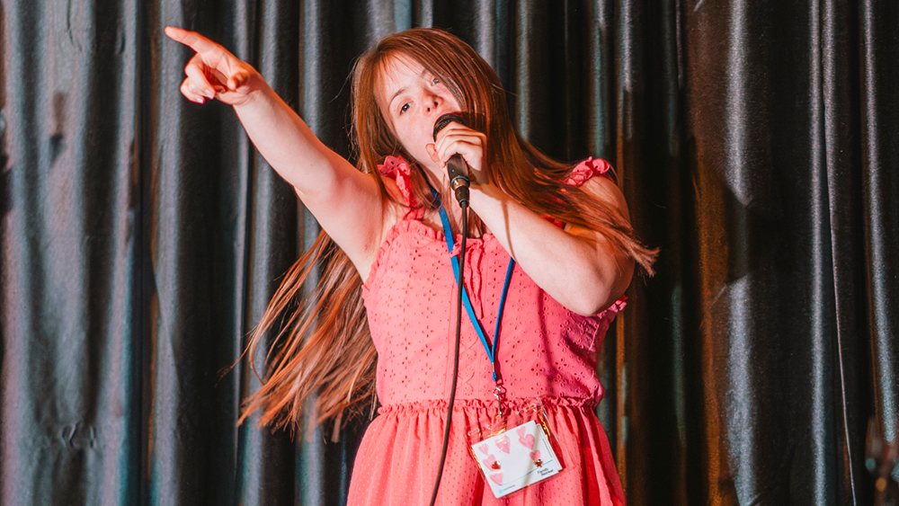 A girl singing and pointing at the crowd