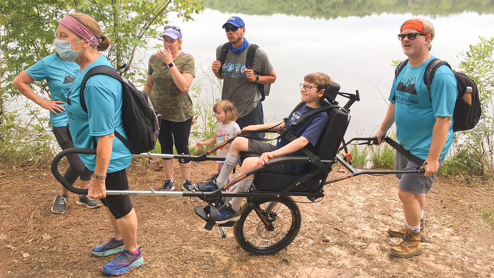 Hikers helping a boy in a specialized wheelchair on the trail