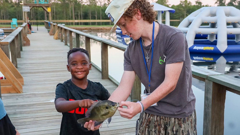 A volunteer holds a fish for a camper