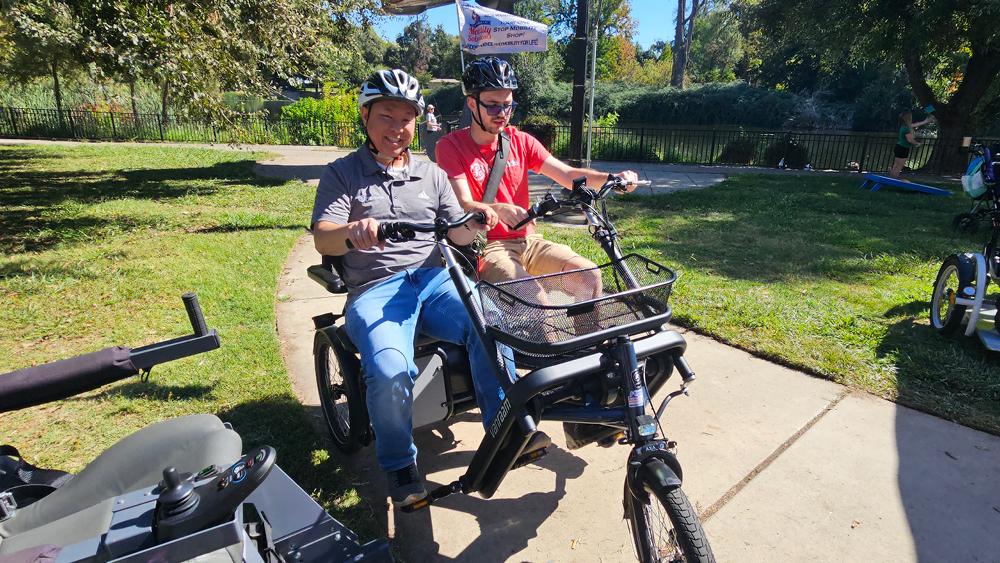 Two guys pose for a photo on a tricycle
