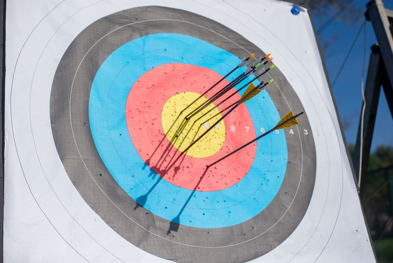Close-up shot of an archery target hit by multiple arrows, achieving a perfect bullseye.