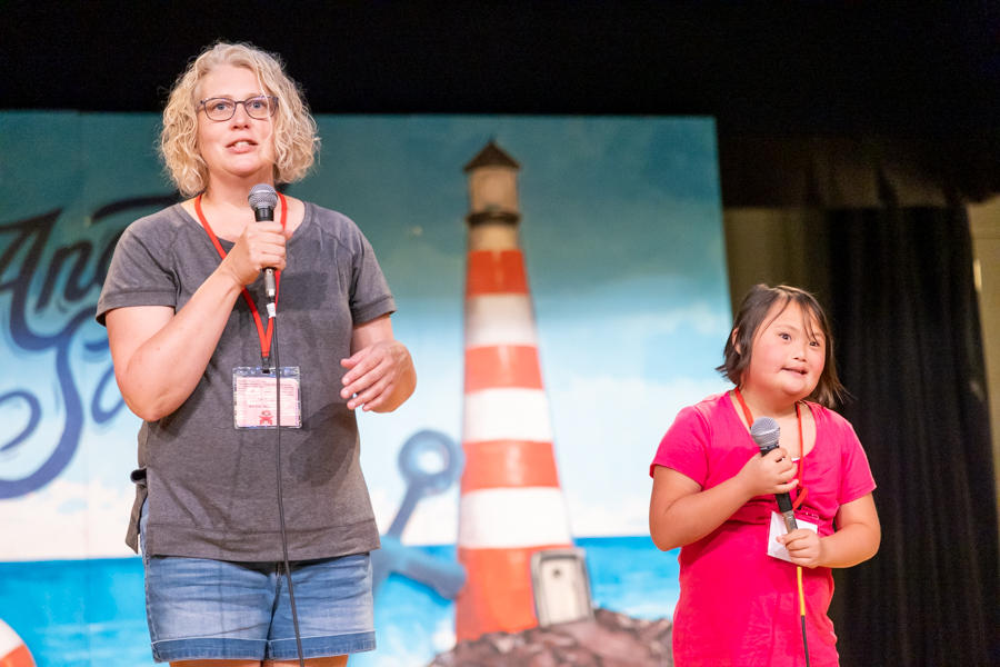 Patricia and Lily stand together on a stage, each holding a microphone.