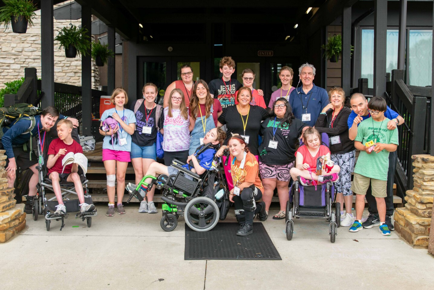 Group photo of children and adults outside a building, several in wheelchairs, smiling at the camera. Group photo of children and adults outside a building, several in wheelchairs, smiling at the camera.